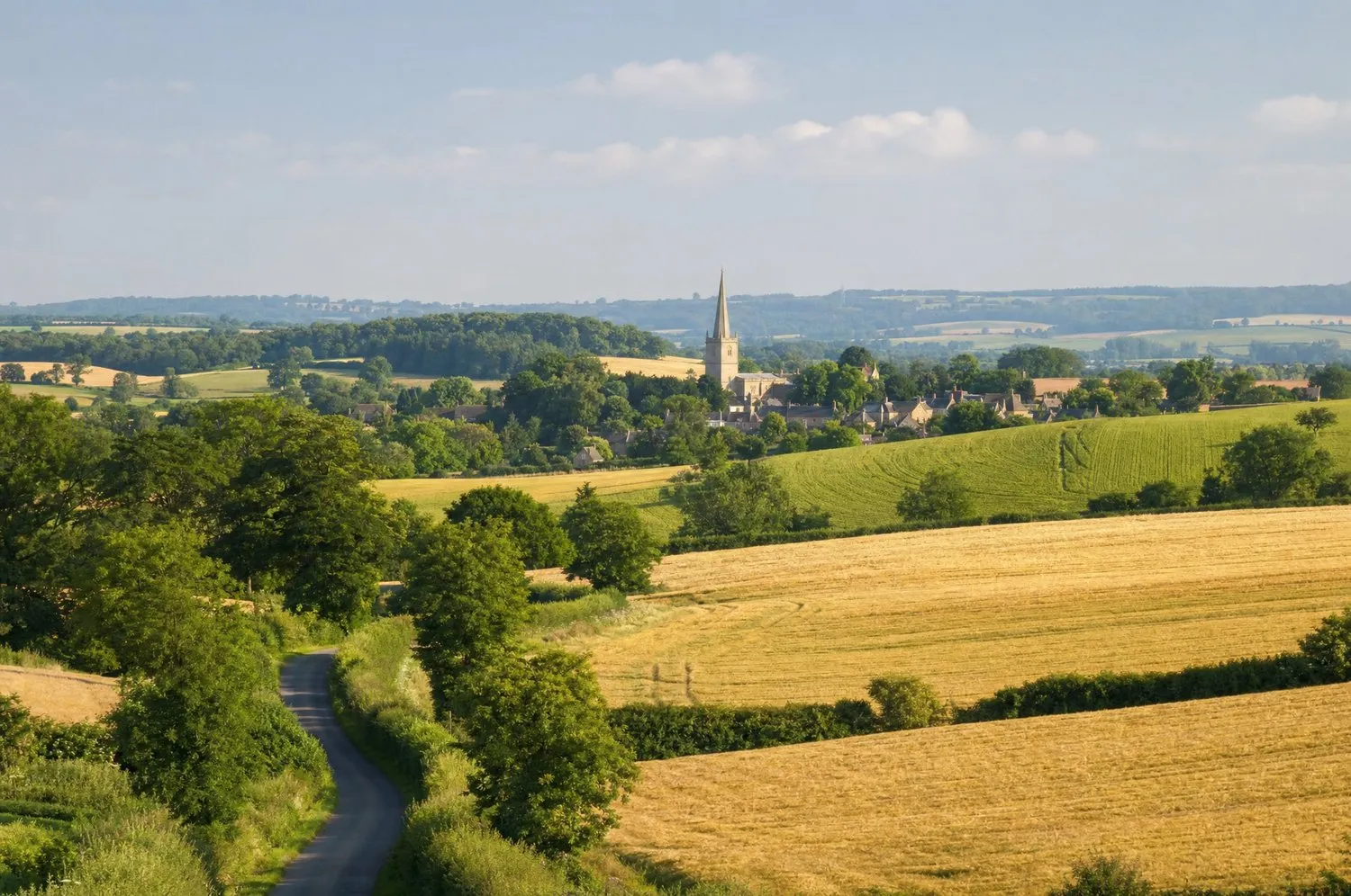Rolling South Northamptonshire farmland with a stone village and church spire in the distance